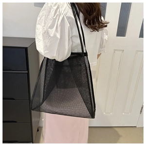 Détail d'un grand sac fourre-tout en maille noire montrant la texture et l'intérieur
