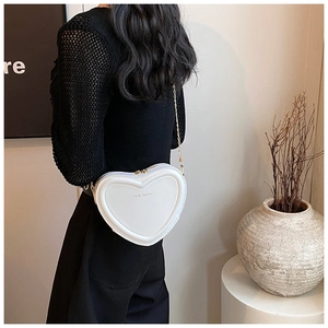Detail der weißen herzförmigen Tasche mit Rich Rabbit Gravur und goldener Kette