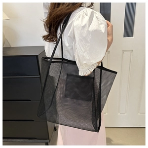Détail du sac cabas en maille noire montrant le côté et la petite poche avant opaque