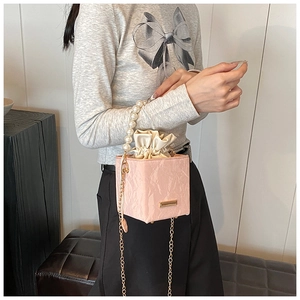 Detail of pink pleated square bucket bag with pearl handle and gold chain strap