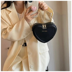 Elegante herzförmige schwarze Umhängetasche mit goldener Kette am Modell gezeigt