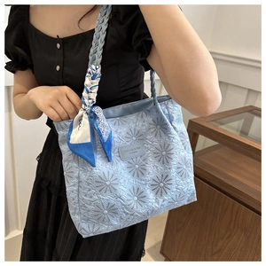 Light blue quilted tote bag with daisy embroidery, braided handles and decorative scarf