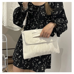 Detail of white pleated envelope bag with cutout handle and slim shoulder strap
