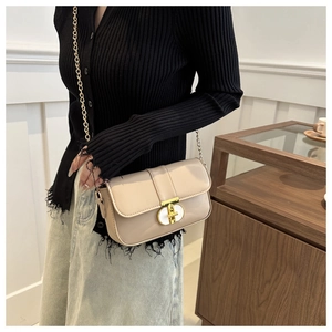 Detail of elegant beige chain crossbody bag with a shiny gold turn-lock closure