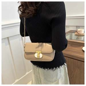 Close-up of khaki crossbody bag with gold chain strap on a model in a cafe
