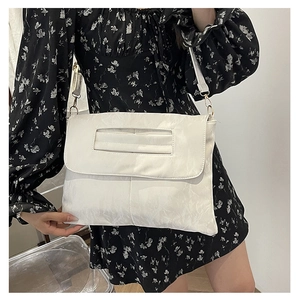 Close-up of minimalist white PU leather crossbody bag with flap and metal buckle