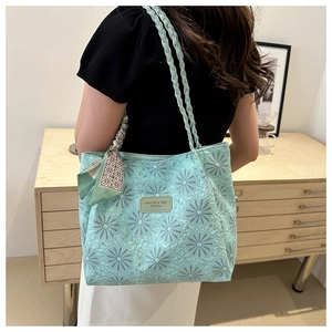 Detail of light green quilted tote bag with floral embroidery and floral ribbon on shoulder