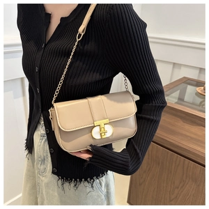 Close-up of beige leather crossbody bag with gold T-bar buckle and metal chain strap