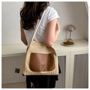 Detail of woven straw tote with brown leather pocket and rope shoulder straps