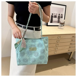 Detail of light green daisy embossed tote bag with braided handle and geometric silk scarf