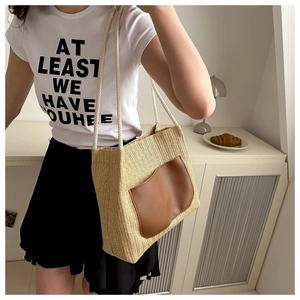 Straw woven tote bag with a brown leather pocket and rope straps shown on a model
