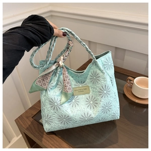 Detail of mint green tote bag featuring daisy embroidery and decorative silk scarf
