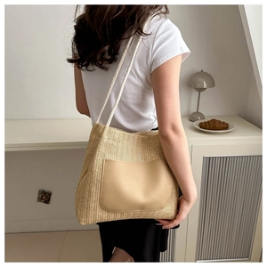 Detail of woven straw tote bag with khaki leather pocket and white rope handles