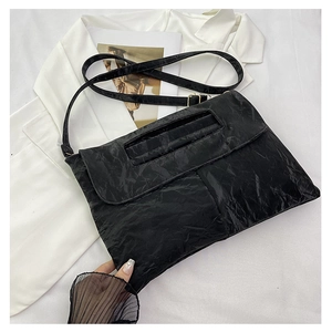 Détail du sac enveloppe noir en PU plissé avec poignée ajourée et boucle dorée