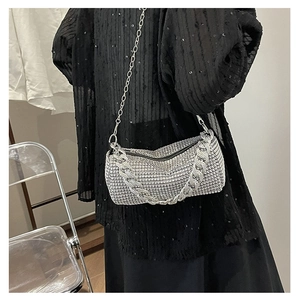 Détail du sac à main argenté orné de strass avec double chaîne porté par un mannequin