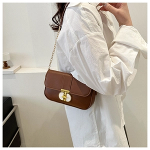 Detail of a brown square shoulder bag with gold chain strap and stylish rotary lock
