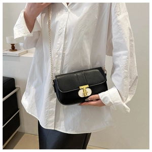 Detail of black leather crossbody bag with golden T-shaped twist lock and chain strap