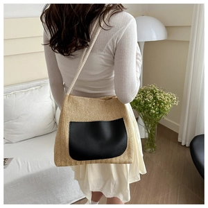 Detailed view of straw shoulder bag with black leather pocket on cream sofa background