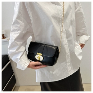 Detail of minimalist black leather crossbody bag with elegant gold chain and oval lock