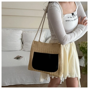 Detail of hand-woven straw tote bag with black leather pocket and cotton rope strap