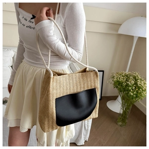 Détail du sac cabas en paille tissée avec poche en cuir noir et bandoulière en corde de coton