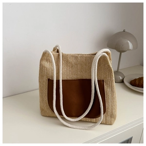 Detail of straw woven tote with brown leather pocket and thick white rope handles