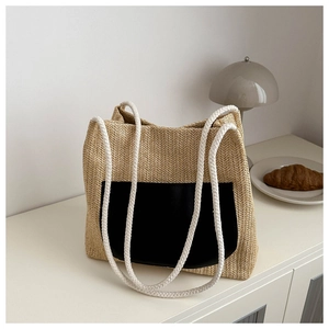 Detail of woven straw tote bag with black faux leather pocket and white cotton rope handles