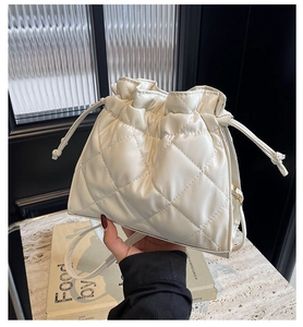 Detail of white quilted PU leather bucket bag with drawstring closure and gold hardware