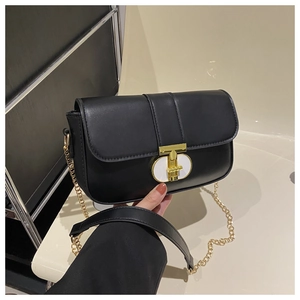 Detail of a black flap crossbody bag featuring a unique gold and white T-shaped metal clasp