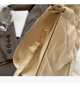 Close-up of beige quilted tote bag with pale gold hardware and adjustable leather strap