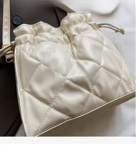 Detail of cream quilted drawstring bucket bag with classic diamond stitching texture