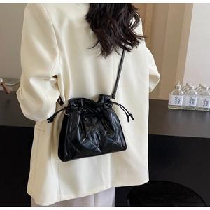 Chic black quilted drawstring bucket bag shown from a back perspective on a model