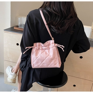Detail of pink quilted drawstring bucket bag with shiny finish on black clothing