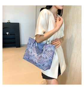 Close-up of tote bag with blue wave pattern print and elegant pearl chain detail