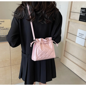 Detail of pink quilted PU leather crossbody bag with drawstring closure and ruffle design