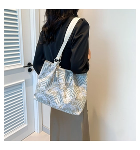 Close-up of elegant canvas tote with artistic wave pattern and pearl tassel accessory