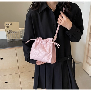 Detailed close-up of a pink quilted bucket bag featuring a drawstring closure and a slim strap