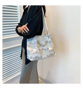 Detail of large tote bag with wave pattern, pearl handle decoration and leather strap