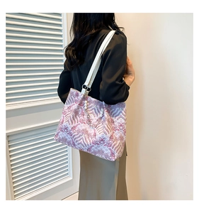 Detail of elegant purple wave pattern fabric tote bag with white straps and pearl charm