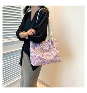 Detail of elegant wavy pattern fabric and pearl chain on the purple tote bag