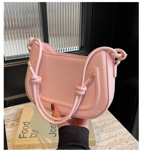 Detailed view of pink saddle bag with knot strap and gold metal hardware accents