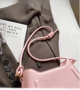 Detail of pink saddle bag with cylindrical knot shoulder strap and golden metal caps