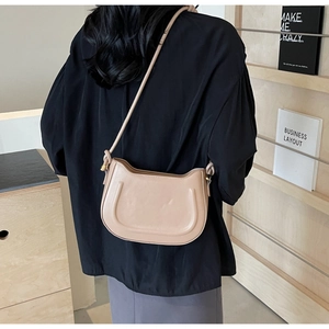 Detail of beige saddle bag with U-shaped decorative lines and adjustable strap