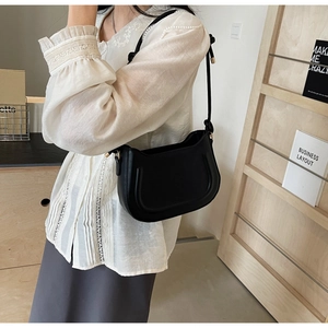 Detail of black semi-circle saddle bag with fine stitching and gold hardware