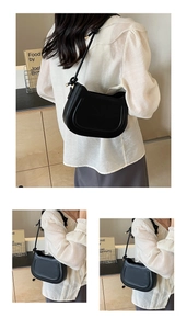 Detail of the black PU shoulder bag showing the U-shaped embossed panel and knot strap