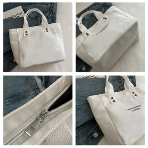 Vue détaillée du sac cabas en toile crème avec rivets métalliques et fermeture éclair