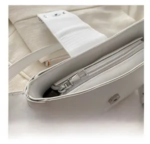 Close-up of the smooth silver zipper and magnetic buckle inside the white PU leather bag