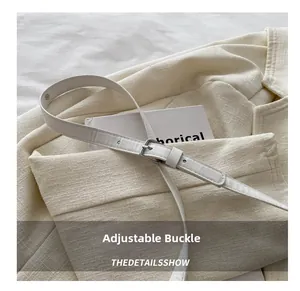 Detail of adjustable silver metal buckle on a beige PU leather belt over a textured blazer