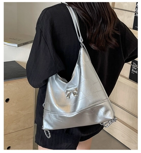 Silver quilted hobo bag detail with metal bow ornament and leather chain strap