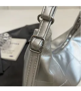 Detail of adjustable silver shoulder strap with metallic buckle on a bucket bag